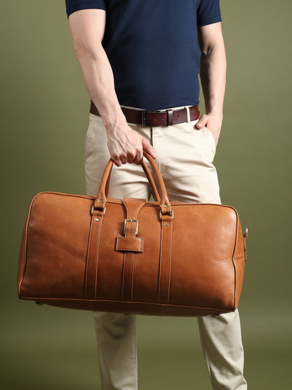 Tan leather duffle bag with center lock clasp, carried by a model