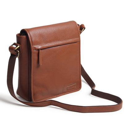 Brown leather crossbody bag side view with flap, metal hardware, and long strap