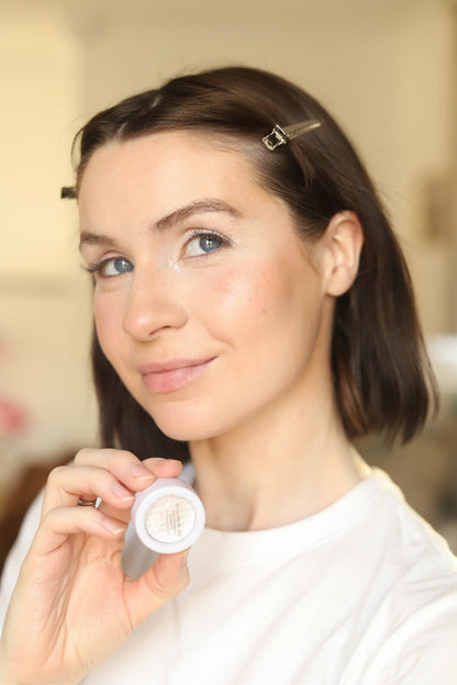 Woman holding a round eyeshadow compact near her face