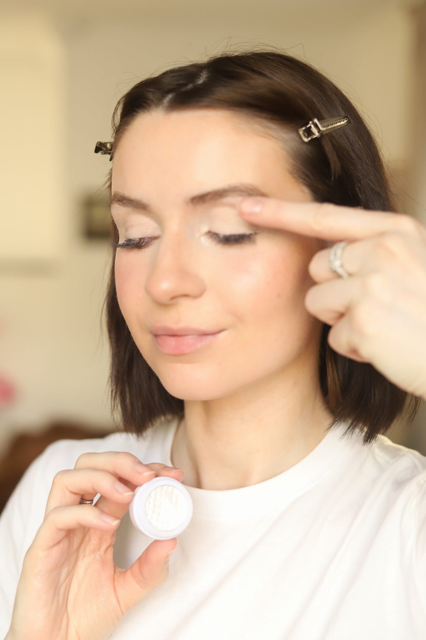 Woman applying eyeshadow with a brush while holding a compact