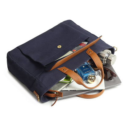 Open dark blue canvas briefcase with tan handles and assorted notebooks inside