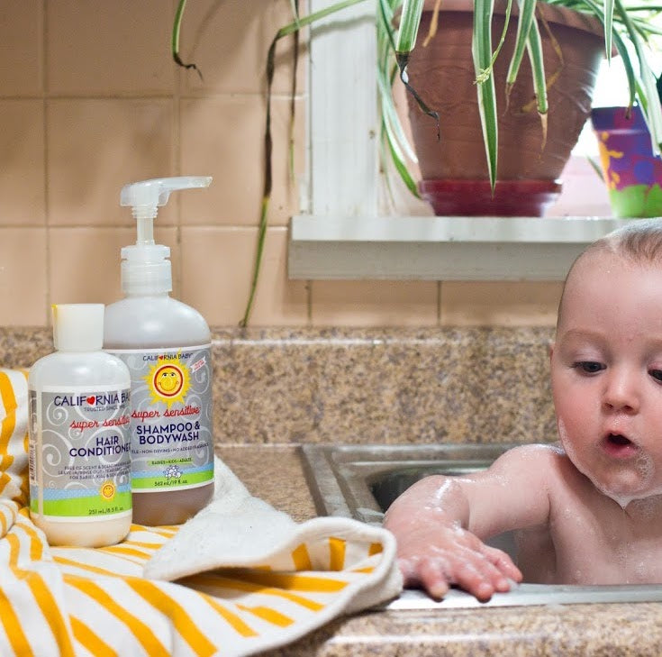 Baby bathing essentials bottles on bathroom counter beside towel