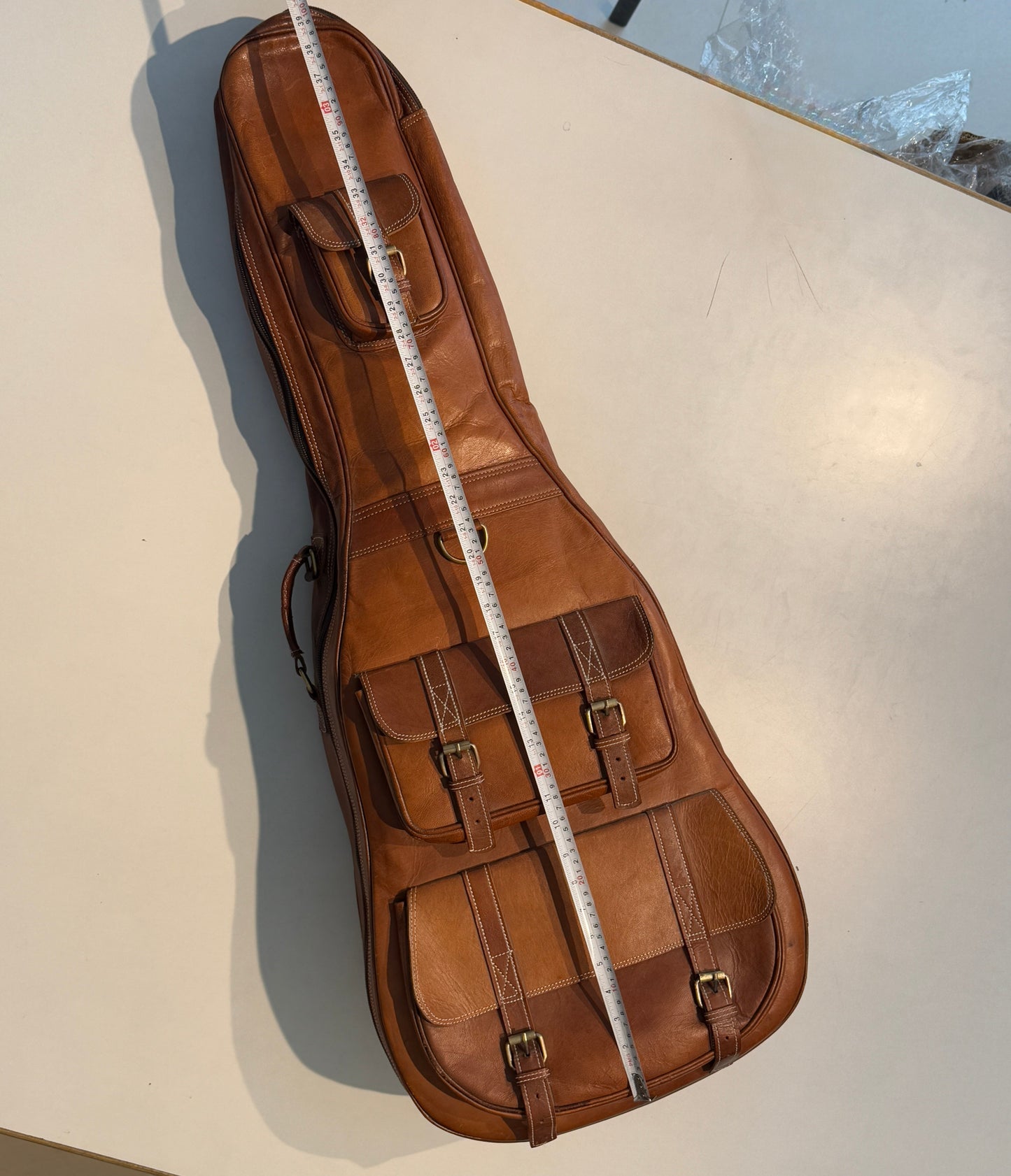 Brown leather guitar case with side handle and padded strap