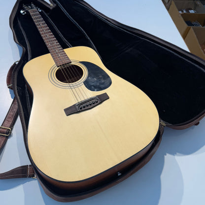 Brown leather guitar case holding a guitar with beige body