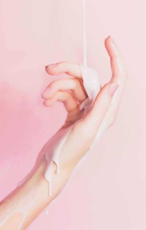 Skincare hand cream application on hands with white lotion