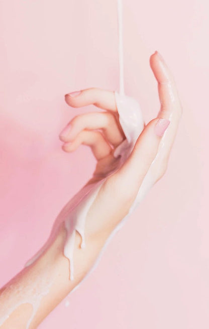 Skincare hand cream application on hands with white lotion