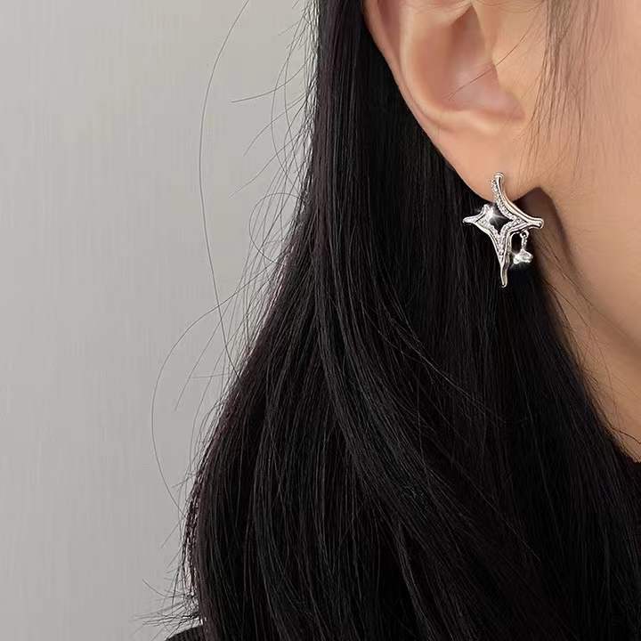 Silver rhinestone star cross earrings on ear, small stud and charm