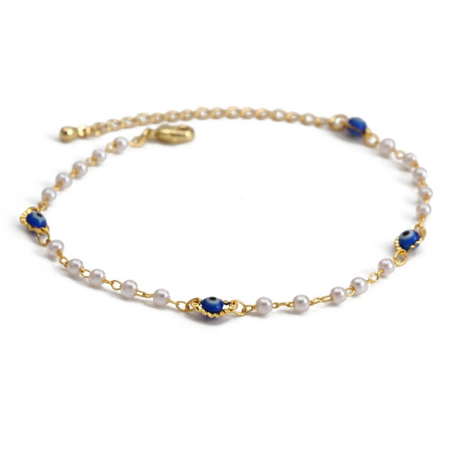 Gold charm bracelet with white pearl-like beads and blue evil-eye charms, with clasp