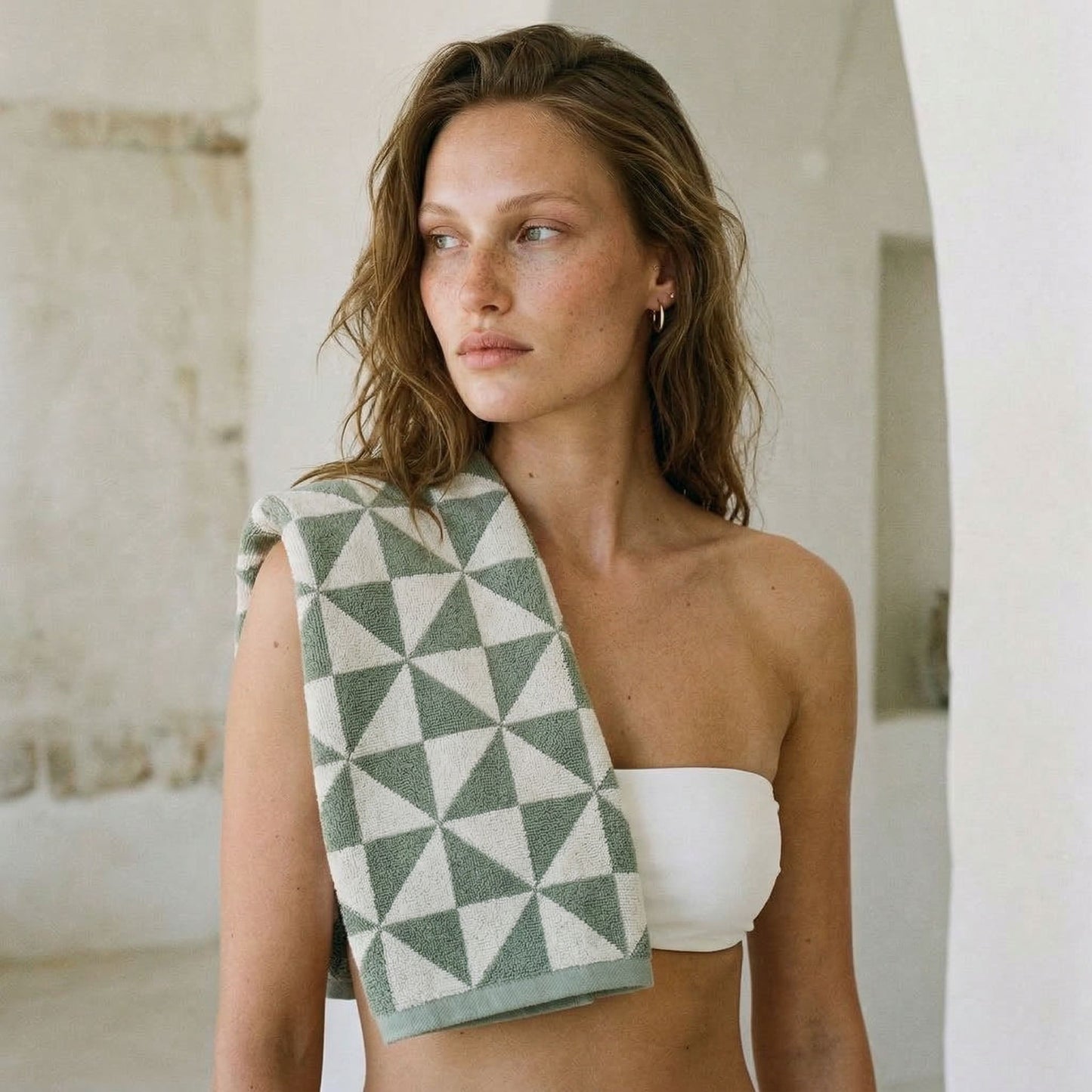 Cotton beach towel draped over shoulder, gray-green and white geometric triangle pattern