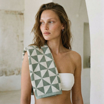 Cotton beach towel draped over shoulder, gray-green and white geometric triangle pattern