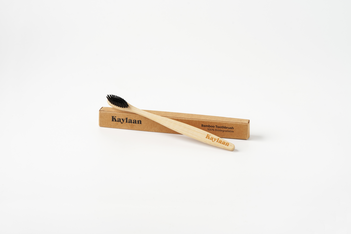 Kaylaan bamboo toothbrush angled view with black bristles on cardboard sleeve