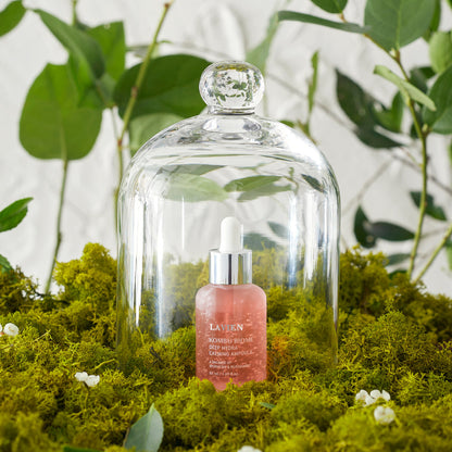Calming ampoule dropper bottle with amber serum under glass dome on moss