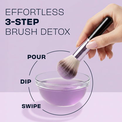 Makeup brush dipping into lavender cleaning solution in a small cup