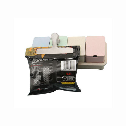Stainless steel chip bag clip securing an opened snack bag, spring latch closed