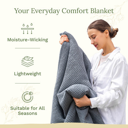 Blue waffle-weave blanket held up by a woman, draped over her arm