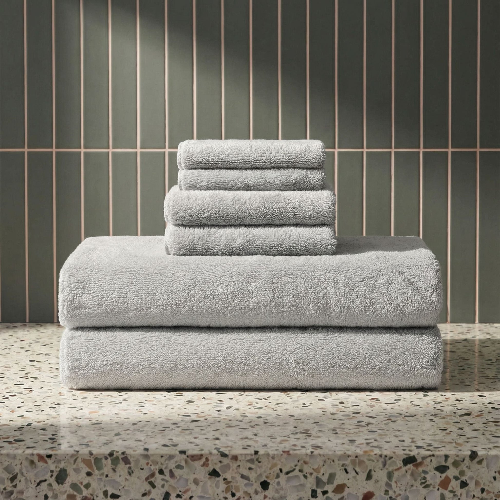 Light gray plush towels stacked in a neat pile, terry loop texture