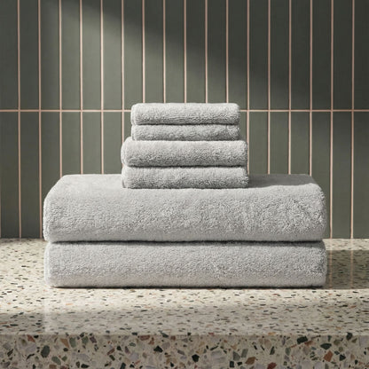 Light gray plush towels stacked in a neat pile, terry loop texture