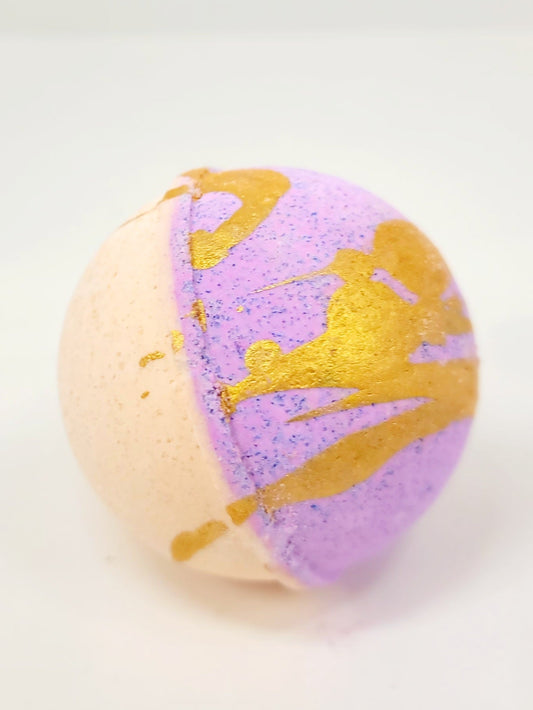 Purple and gold bath bomb with heart-like swirl pattern