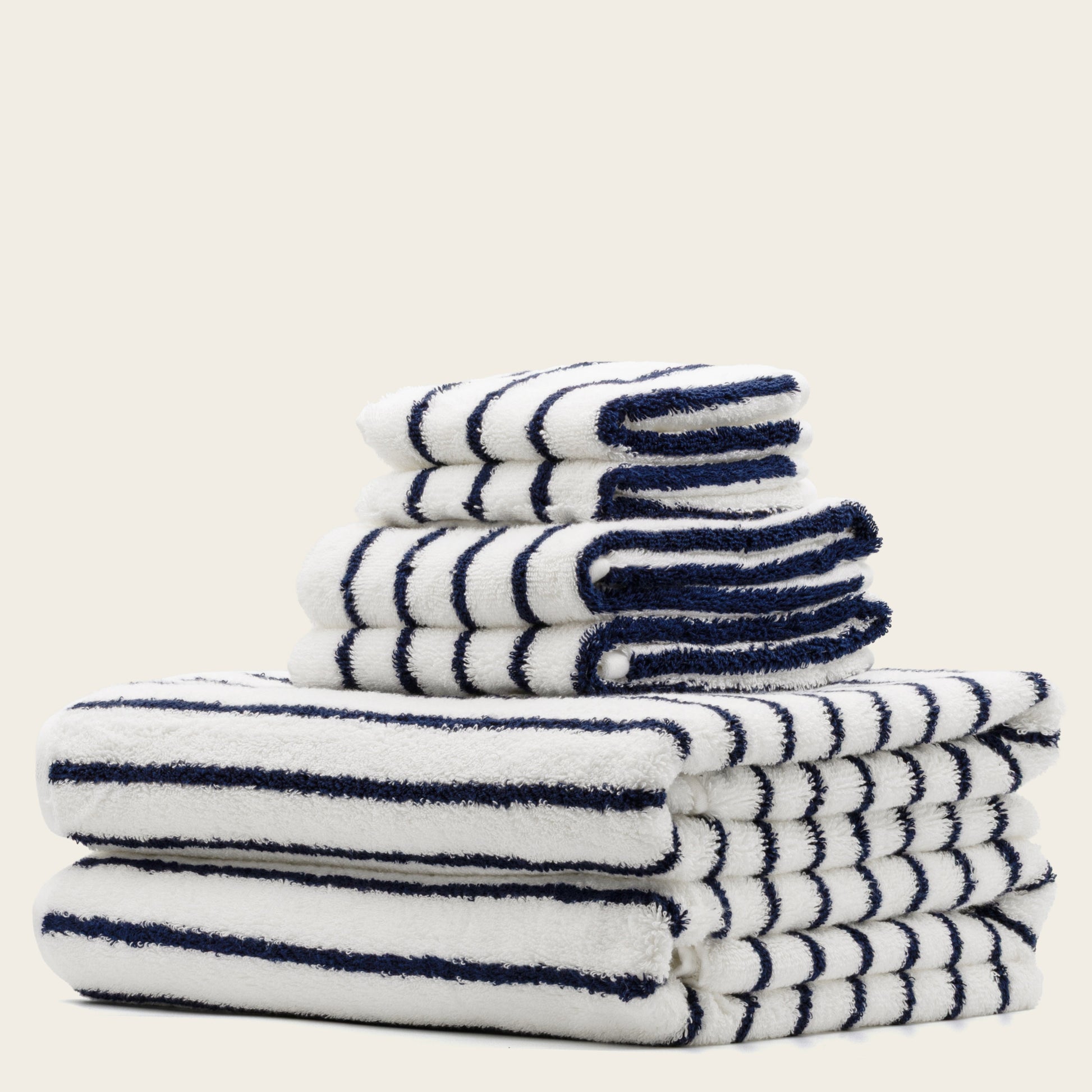 White towels with navy blue stripes, folded stack with plush terry texture.
