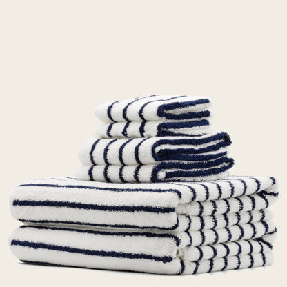 White towels with navy blue stripes, folded stack with plush terry texture.