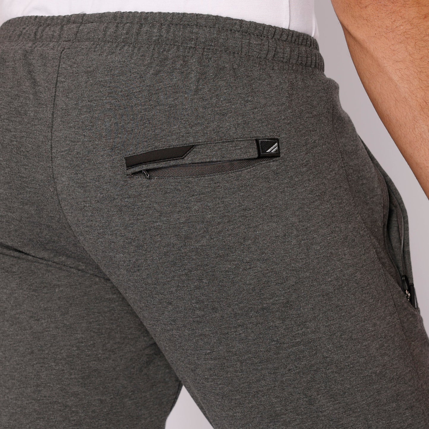 Dark gray athletic sweatpants with tapered leg, elastic waistband, logo patch