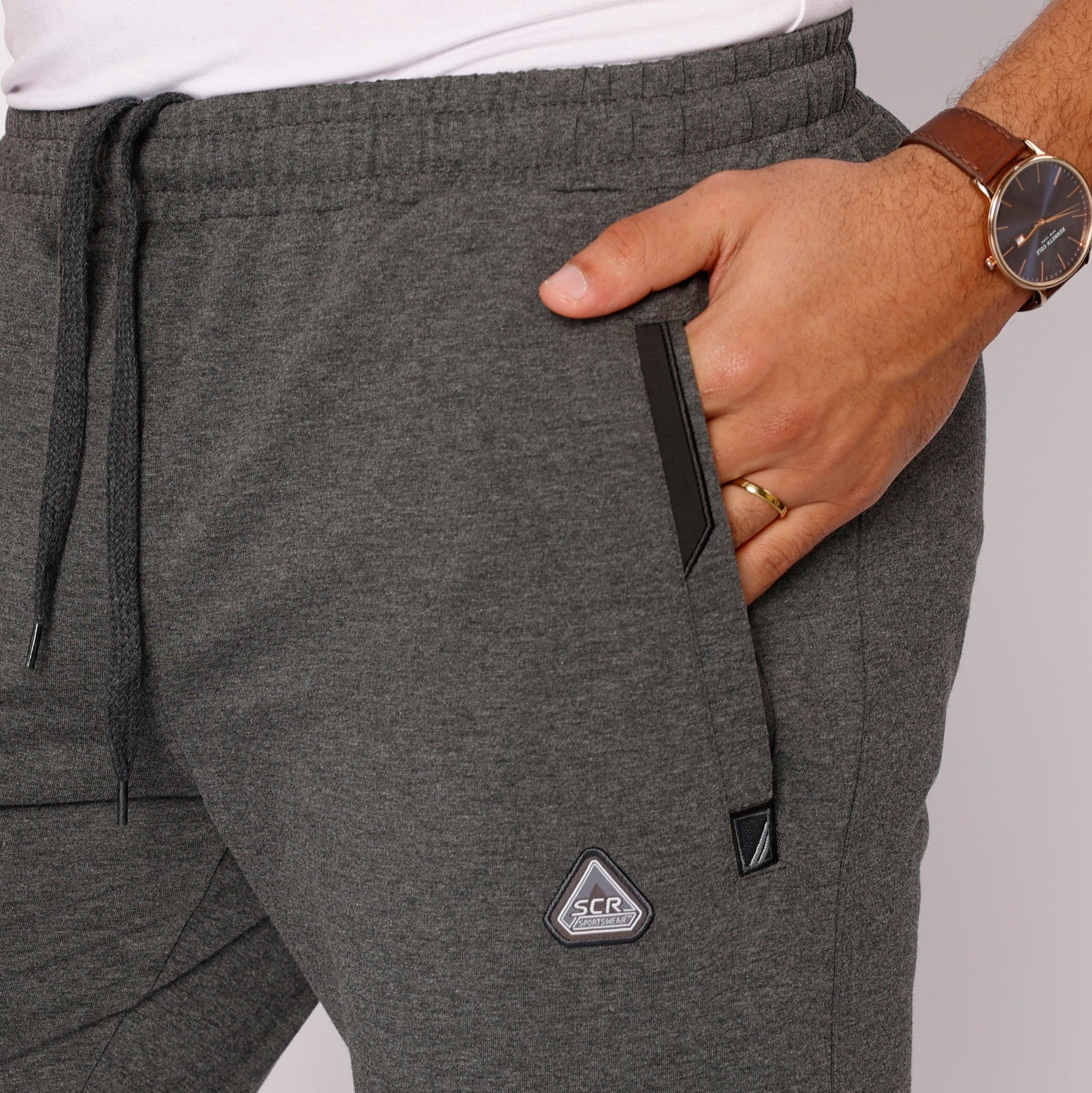 Dark gray tapered sweatpants, drawstring waist, side pockets, logo badge