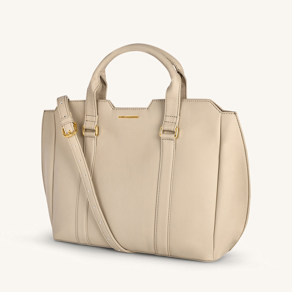 Light taupe crossbody bag with top handle and adjustable strap, stitched panels