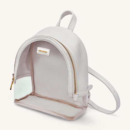 Ivory clear-front mini backpack with gold zipper, logo patch, and crossbody strap