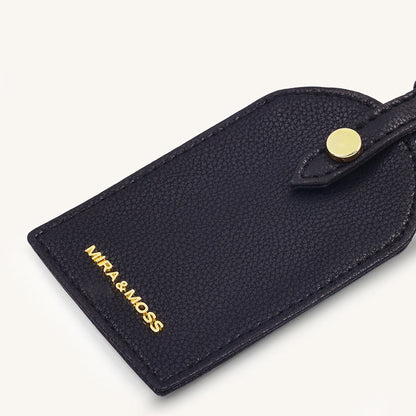 Black textured leather travel tag with gold snap and MIRA&MOSS text