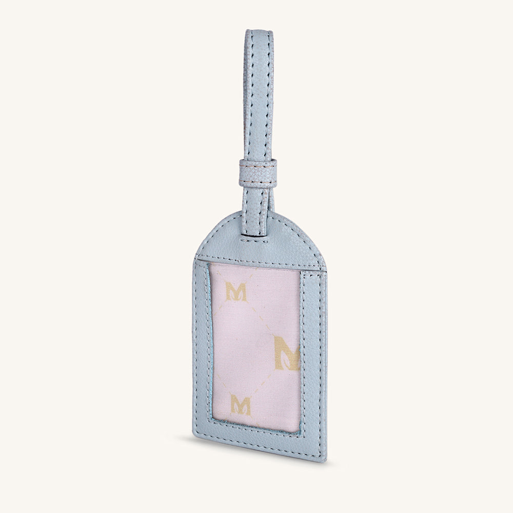 Ice blue travel tag with hanging loop and light pink front panel with gold M letters