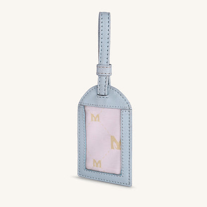 Ice blue travel tag with hanging loop and light pink front panel with gold M letters