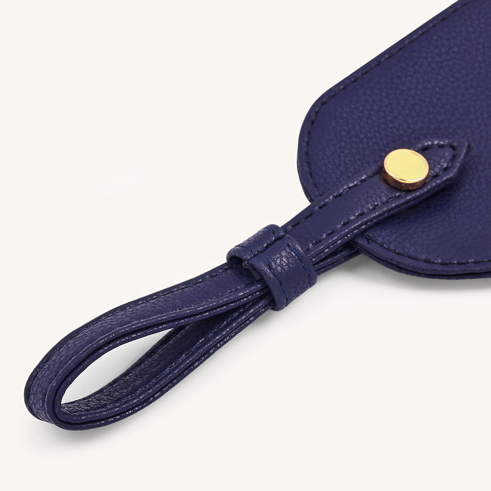 Dark blue travel tag strap close-up with gold snap and stitched edges