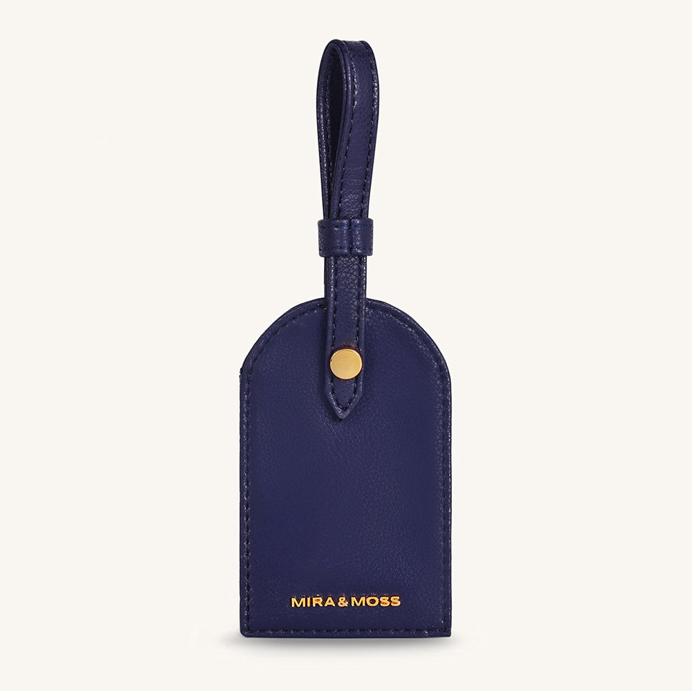 Alexis travel tag in dark blue leather with top loop and gold snap, front logo