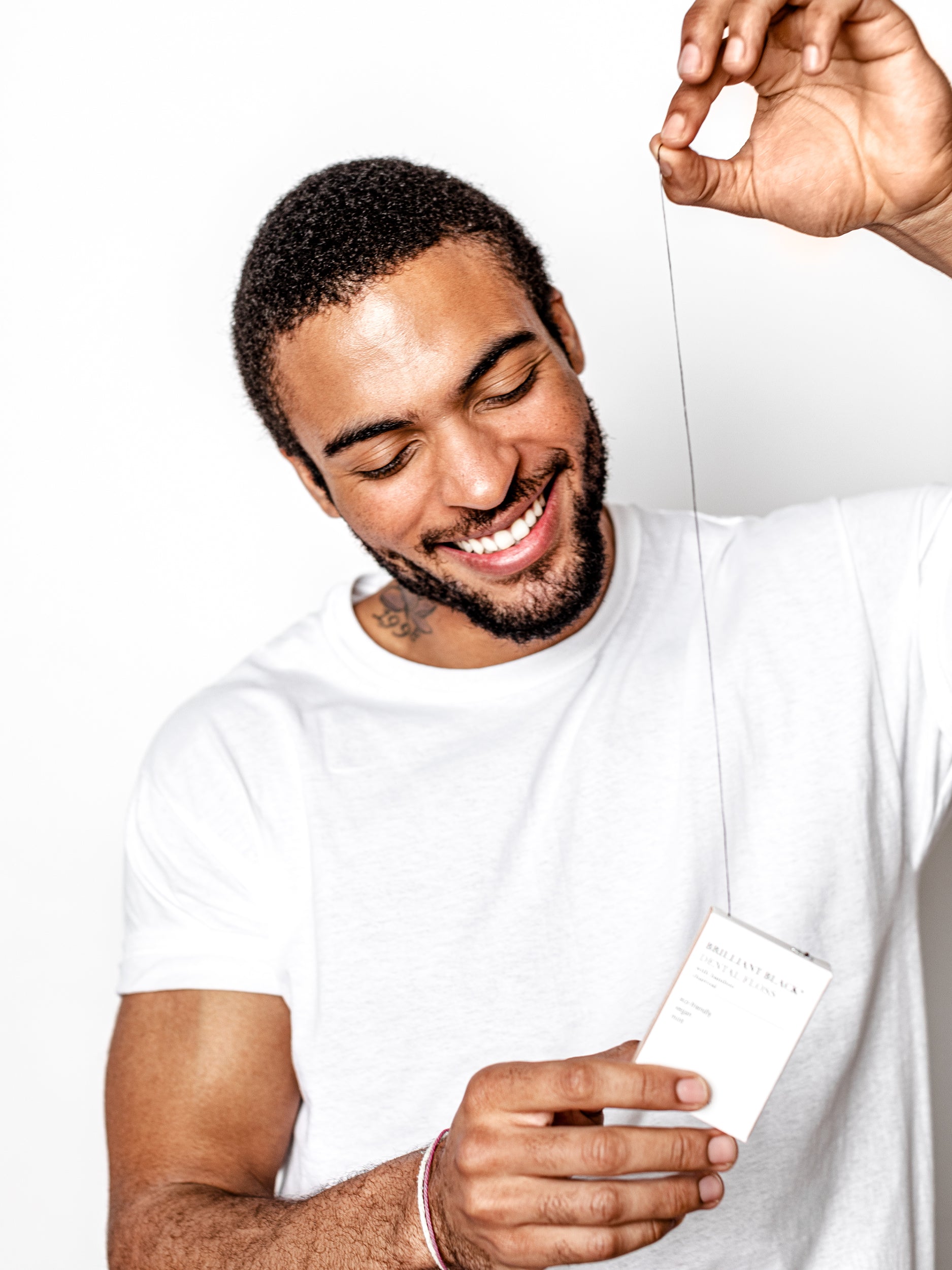 Man holding dental floss box and preparing to floss with the string