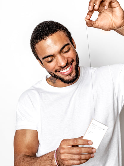 Man holding dental floss box and preparing to floss with the string