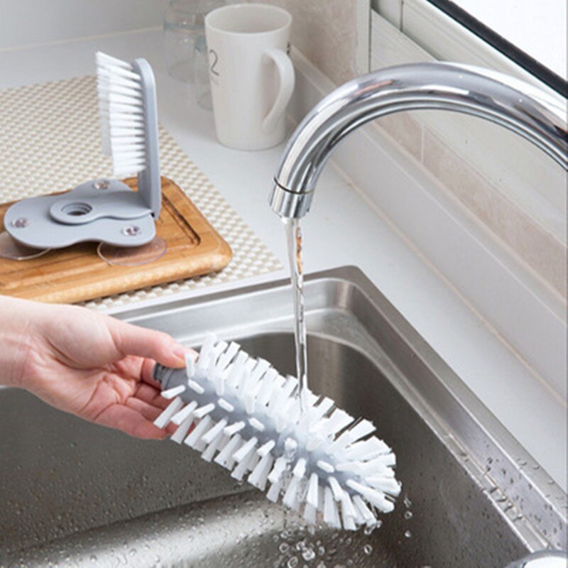 Gray kitchen bottle brush with white bristles, scrubbing inside a sink bottle