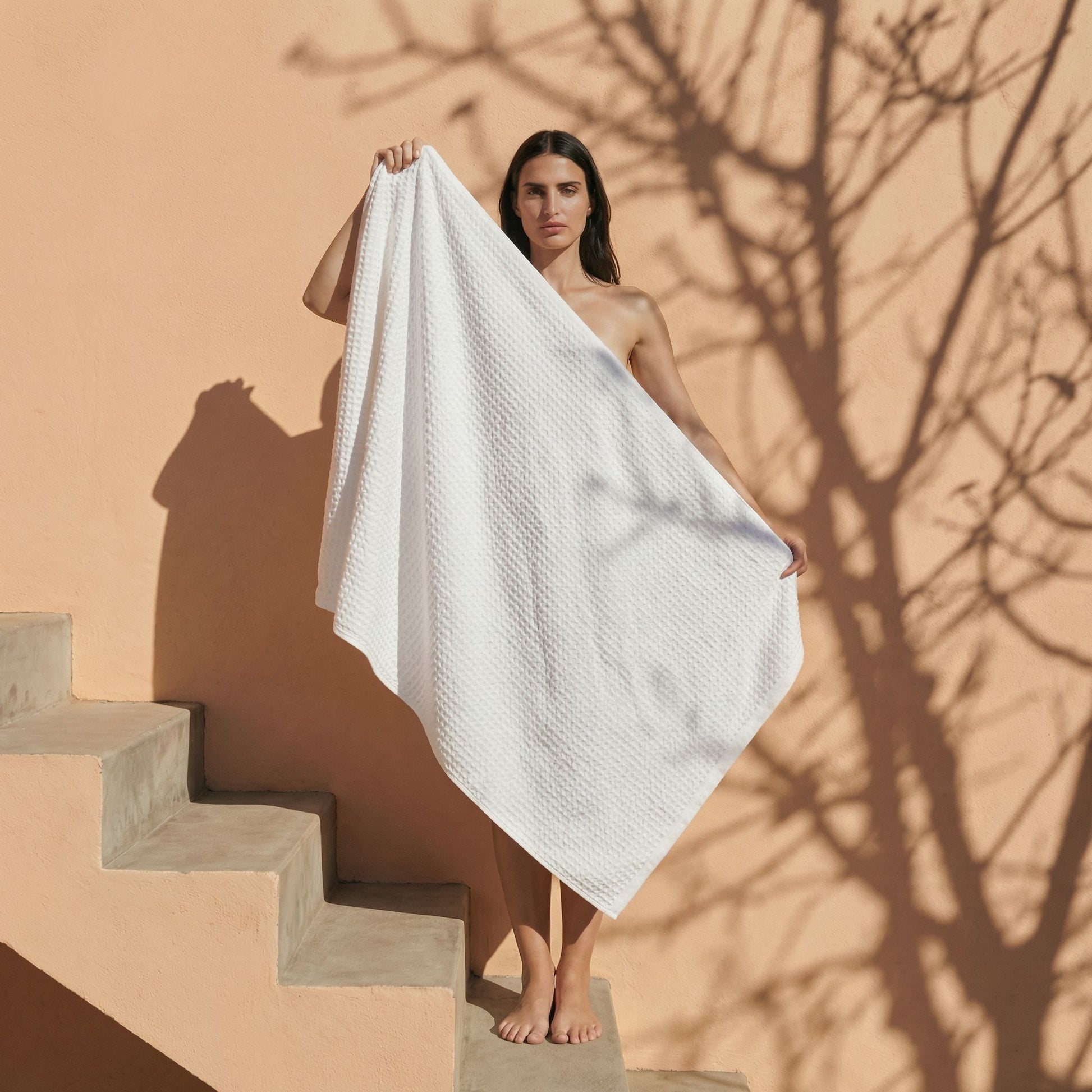 White waffle cotton towel draped over a person’s shoulders, textured waffle pattern.