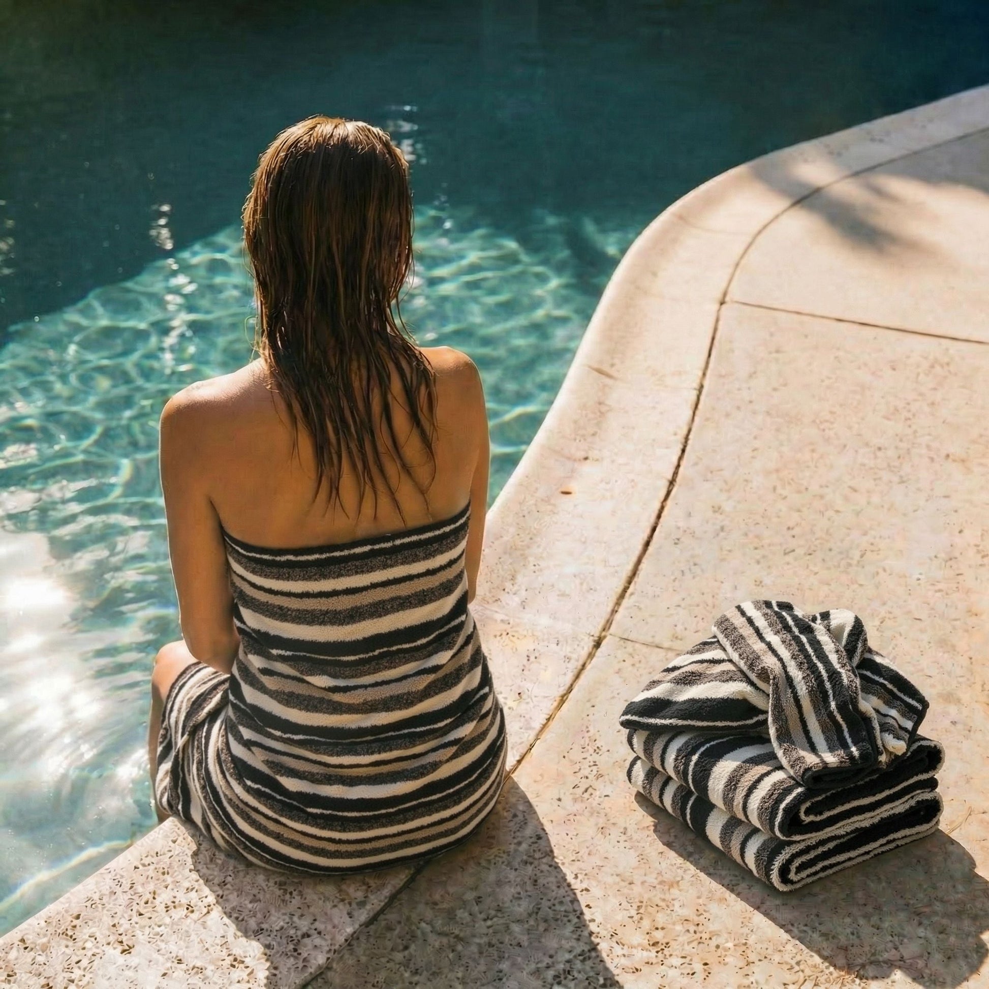 Striped cotton towel, black and white horizontal stripes, folded at pool edge