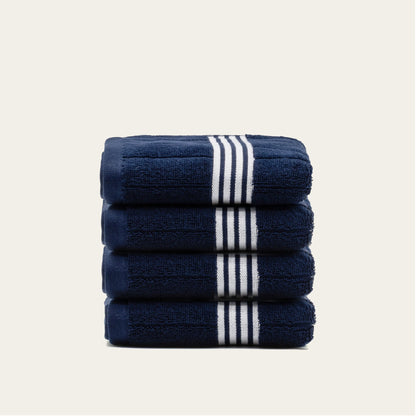 Stacked navy cotton towels with white striped bands, neatly folded