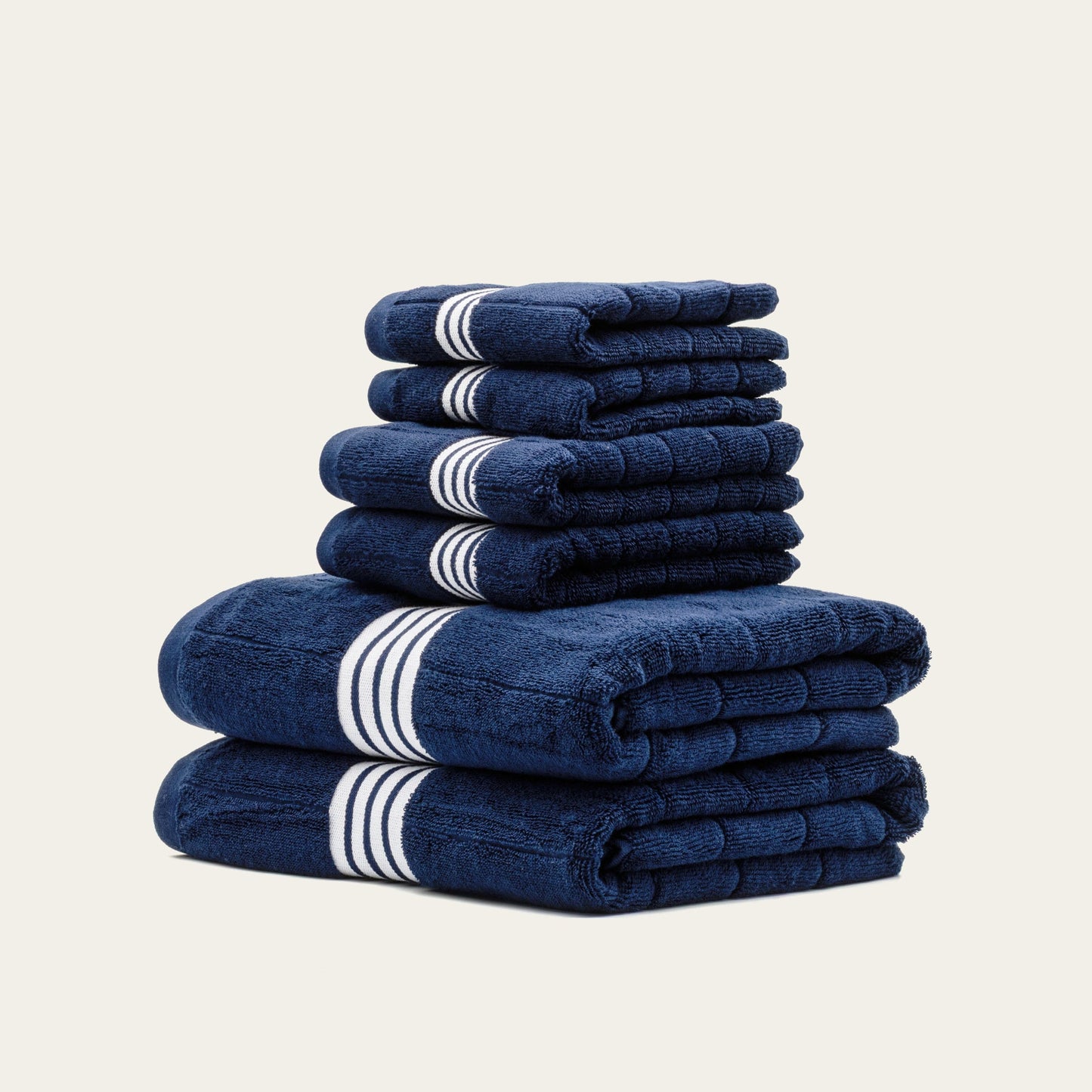Stack of folded navy cotton towels with white striped bands