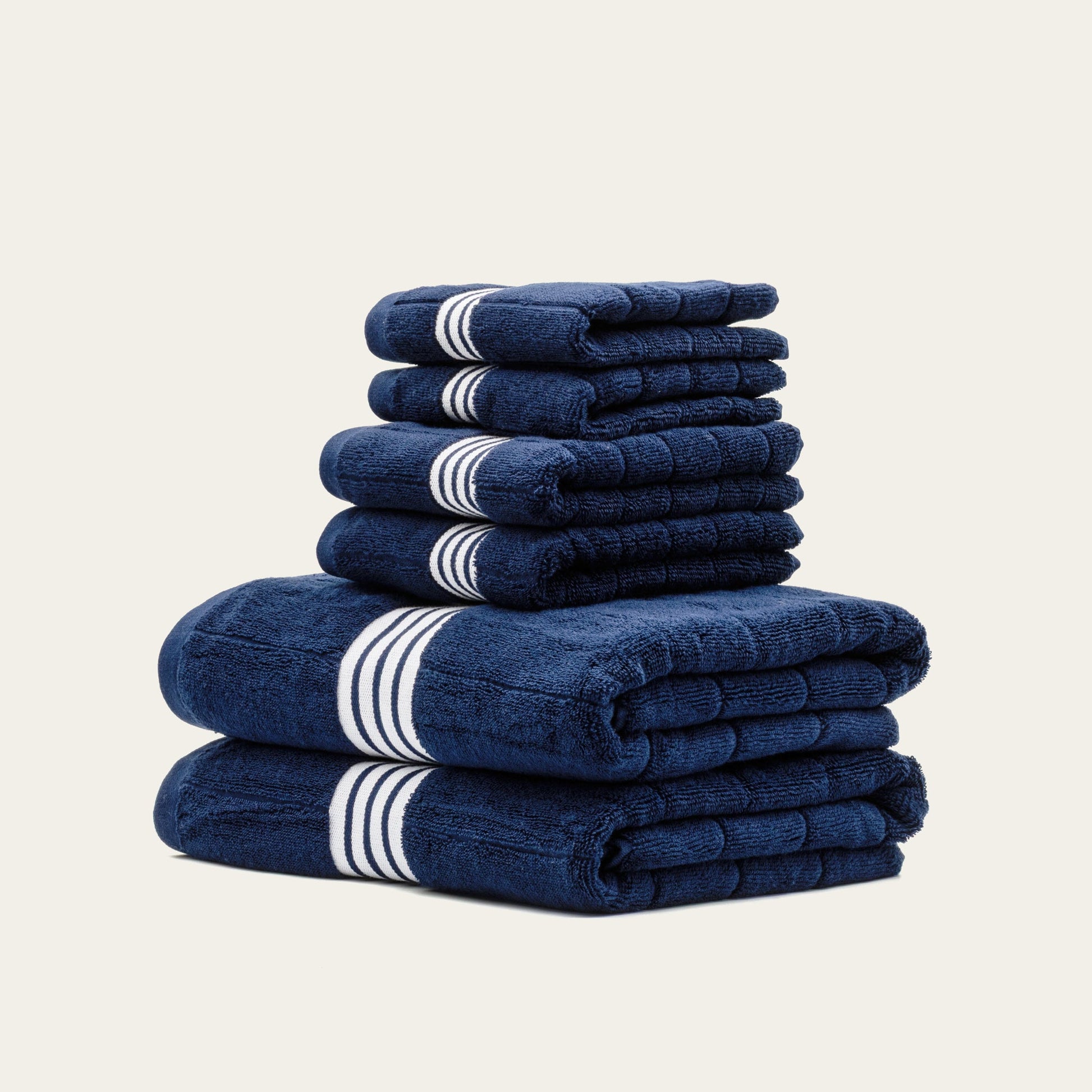 Stack of folded navy cotton towels with white striped bands
