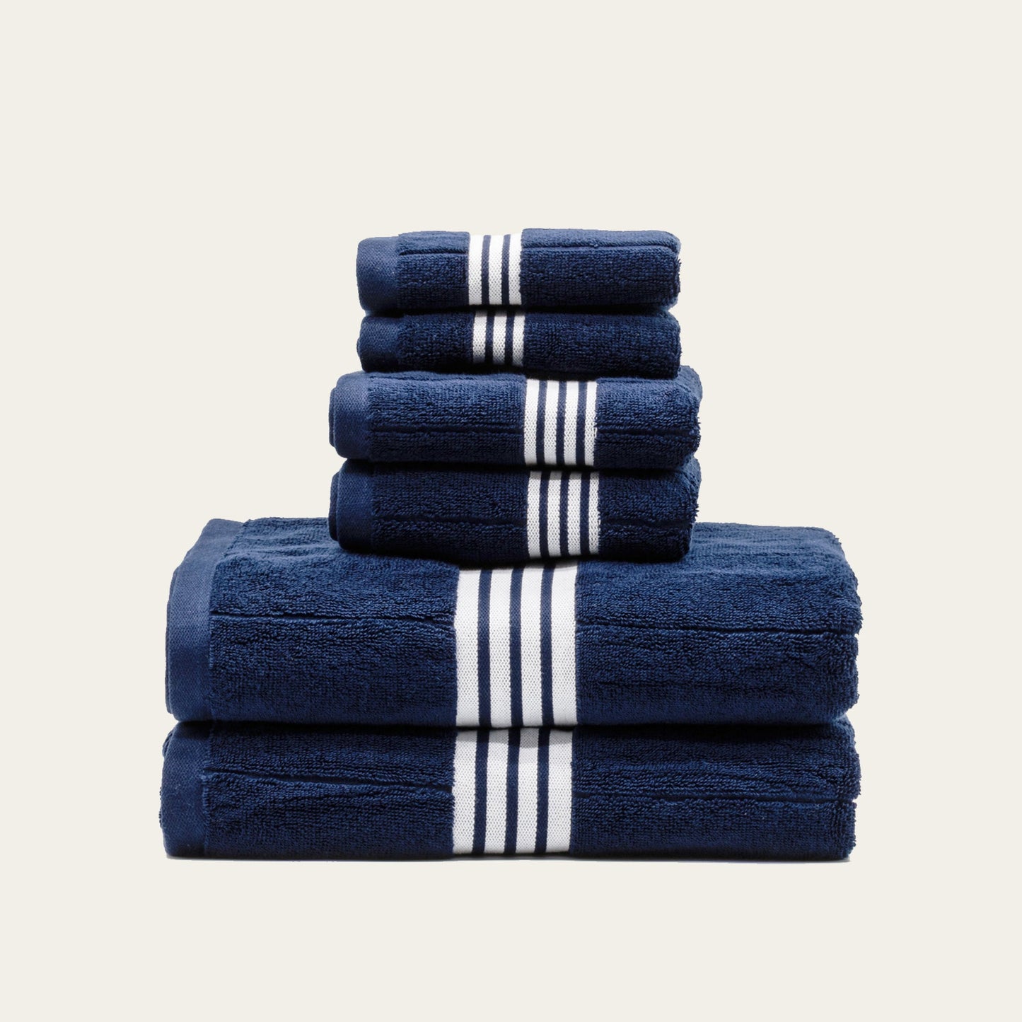 Navy cotton towel set with white striped bands, stacked in tiers