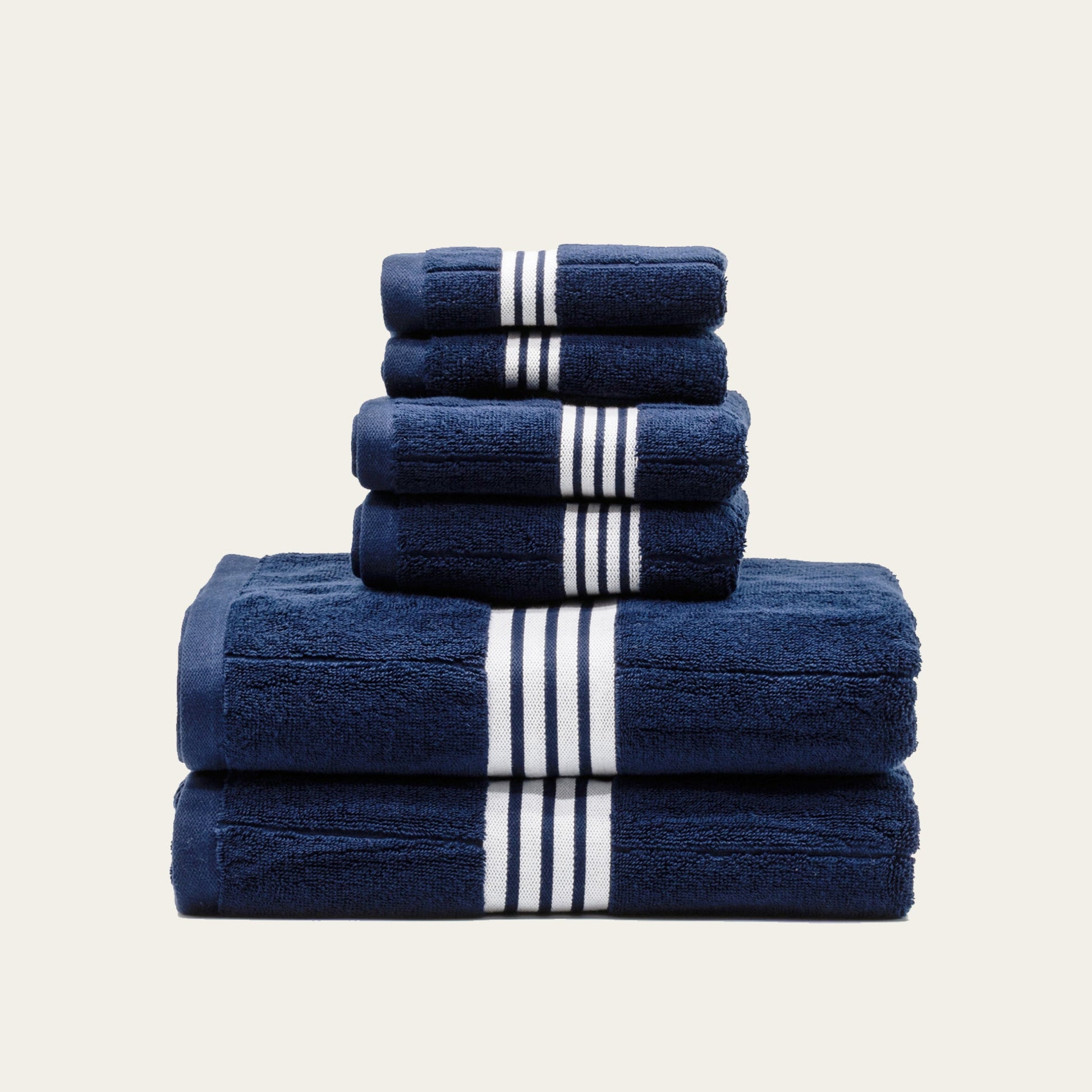 Navy cotton towel set with white striped bands, stacked in tiers