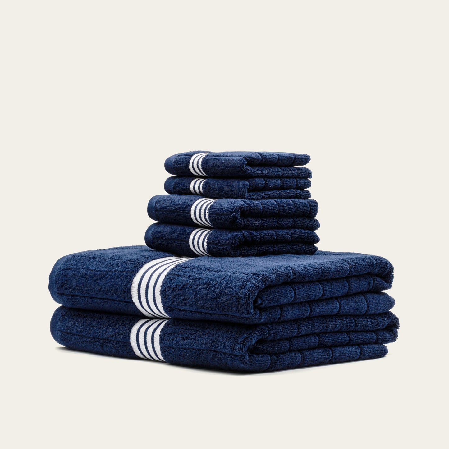 Folded navy cotton towels with white striped bands, layered stack