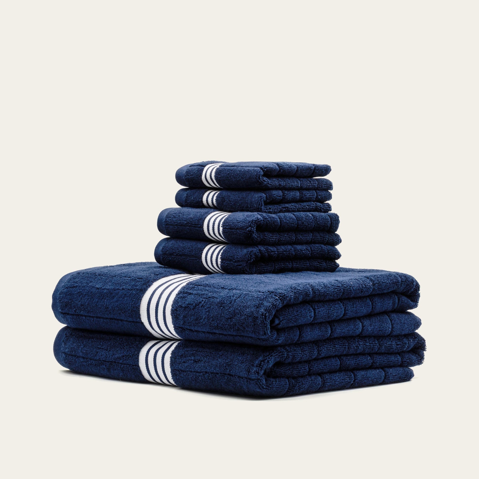 Folded navy cotton towels with white striped bands, layered stack