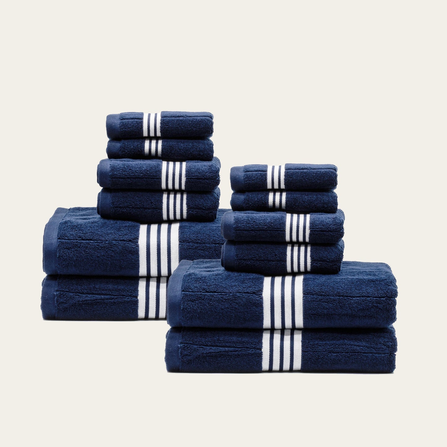 Navy cotton towels set with white striped bands, multiple folded towels arranged in a stack.