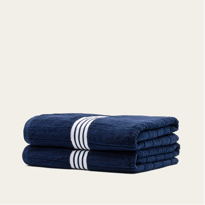 Navy cotton towels set with white striped bands, two folded towels stacked horizontally.
