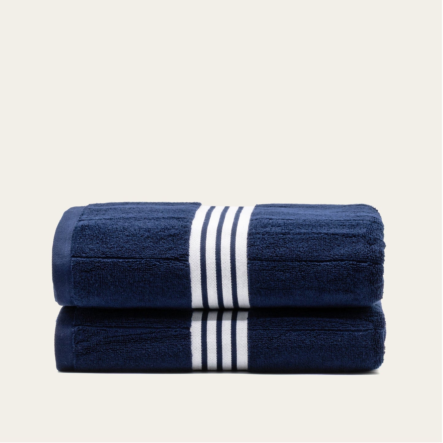 Navy cotton towels set with white striped bands, two folded towels tied with stripe center.