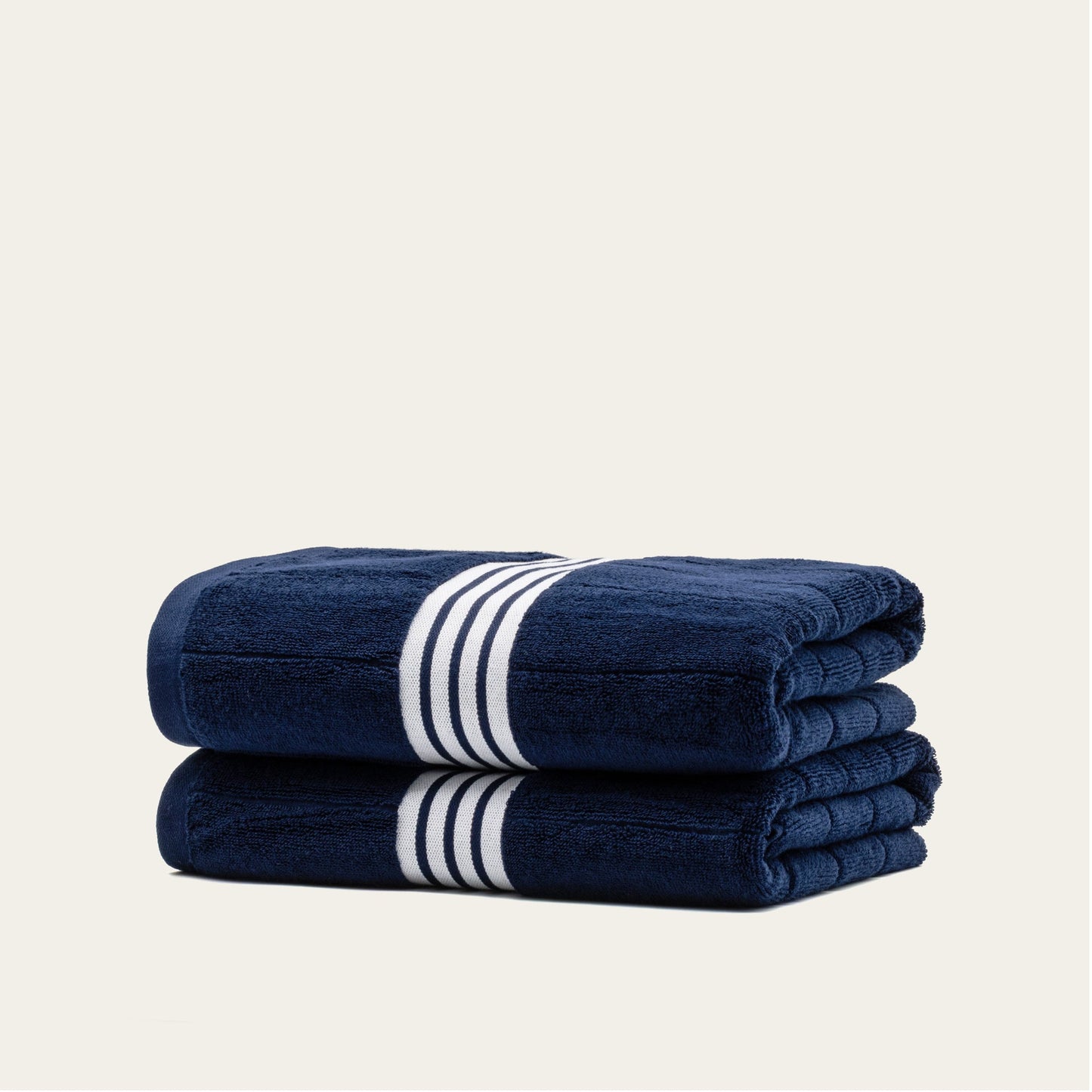Navy cotton towels set with white striped bands, two towels stacked with stripe bands visible.