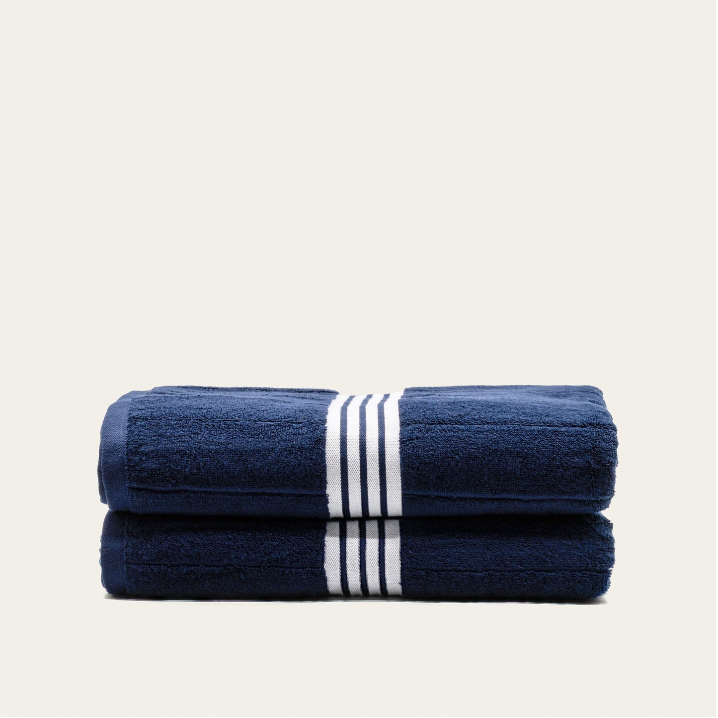 Navy cotton towels set with white striped bands, two rolled folds with a vertical stripe detail.